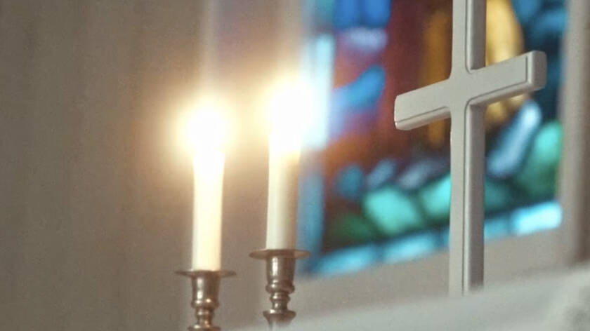 Alttarilla kaksi palavaa kynttilää ja risti.