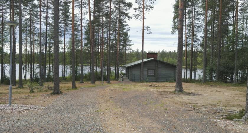 Poikkeusharjun sauna takaapäin, taustalla järvi.